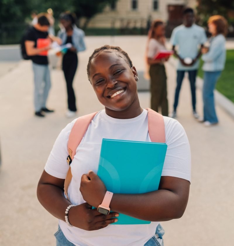 smiling-diverse-college-girl-with-textbook-at-camp-2026-01-09-09-07-41-utc (1) (1)